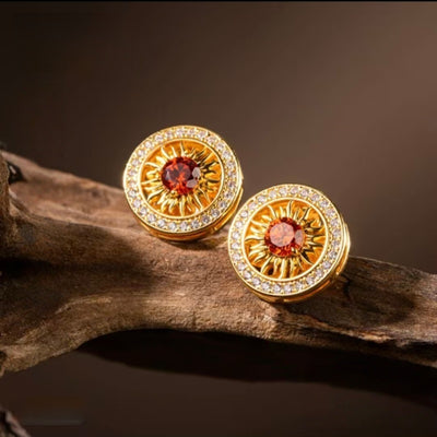 Close-up of the "Solar Core" gold stud earrings, highlighting the detailed sunburst petals and the vibrant red garnet energy anchor.