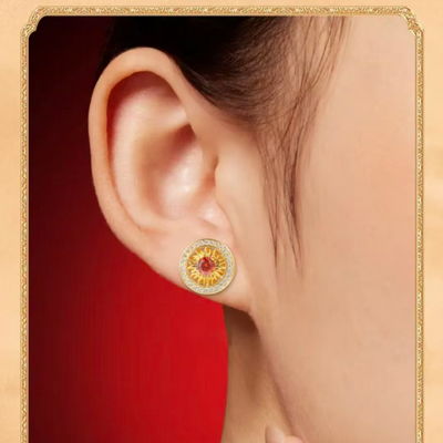 Model wearing AuraNudge "Solar Core" Radiant Studs, gold earrings with a red garnet gemstone, designed to radiate warmth and inner strength.